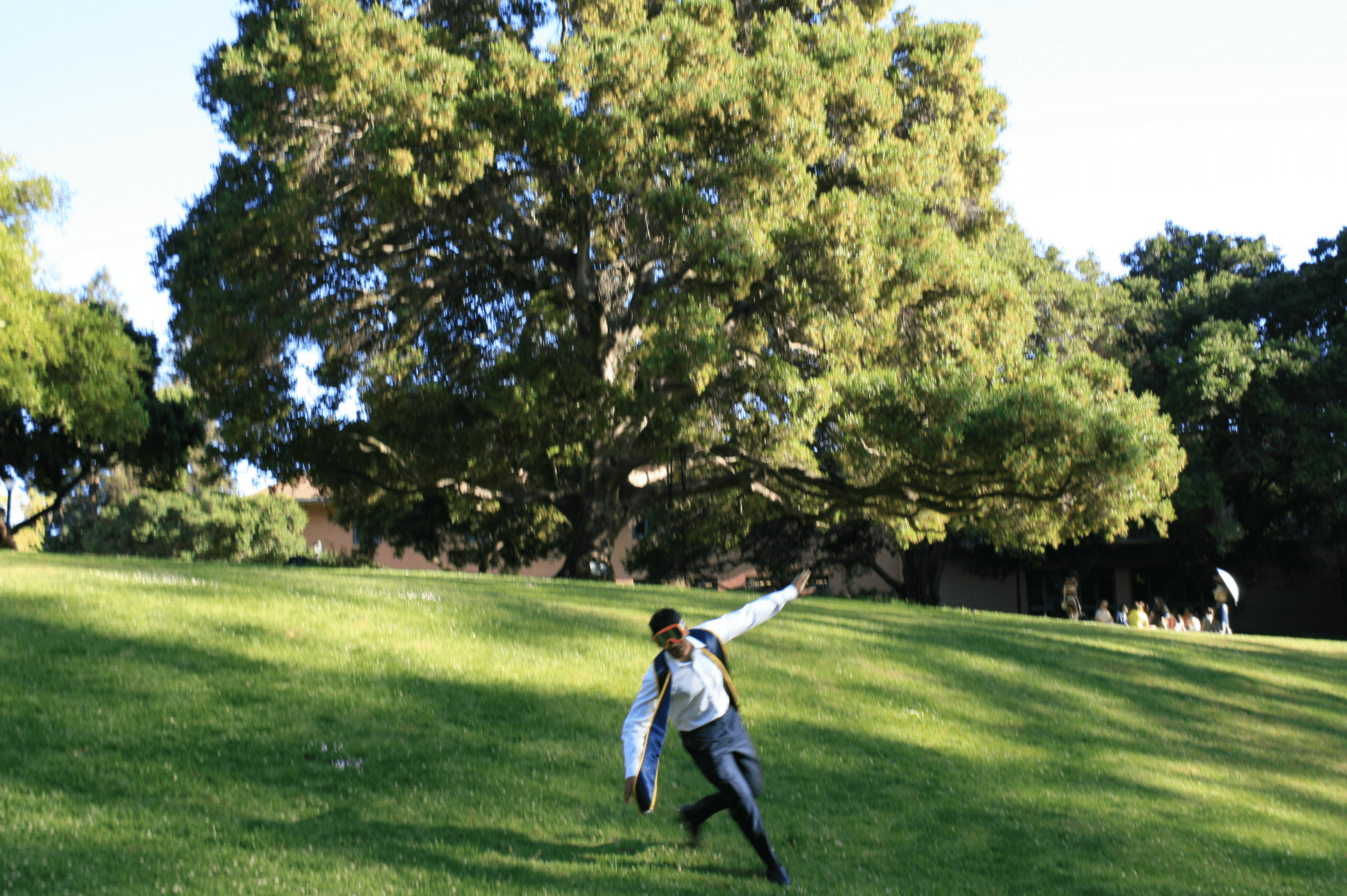 Rishi running across the lawn in UC Berkeley graduation regalia